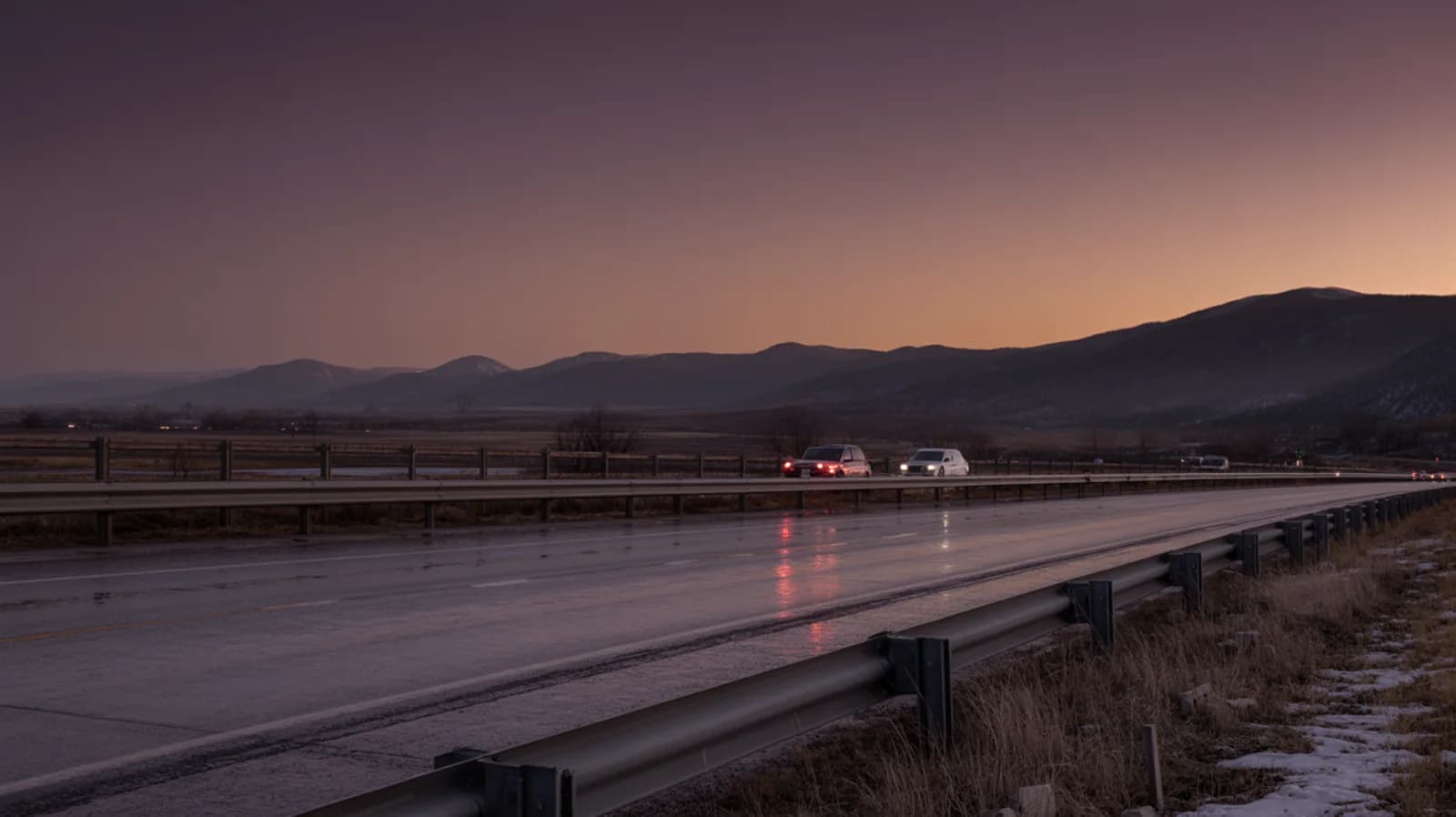 A Colorado highway at dusk with the Front Range foothills silhouetted against a plum and amber sky.