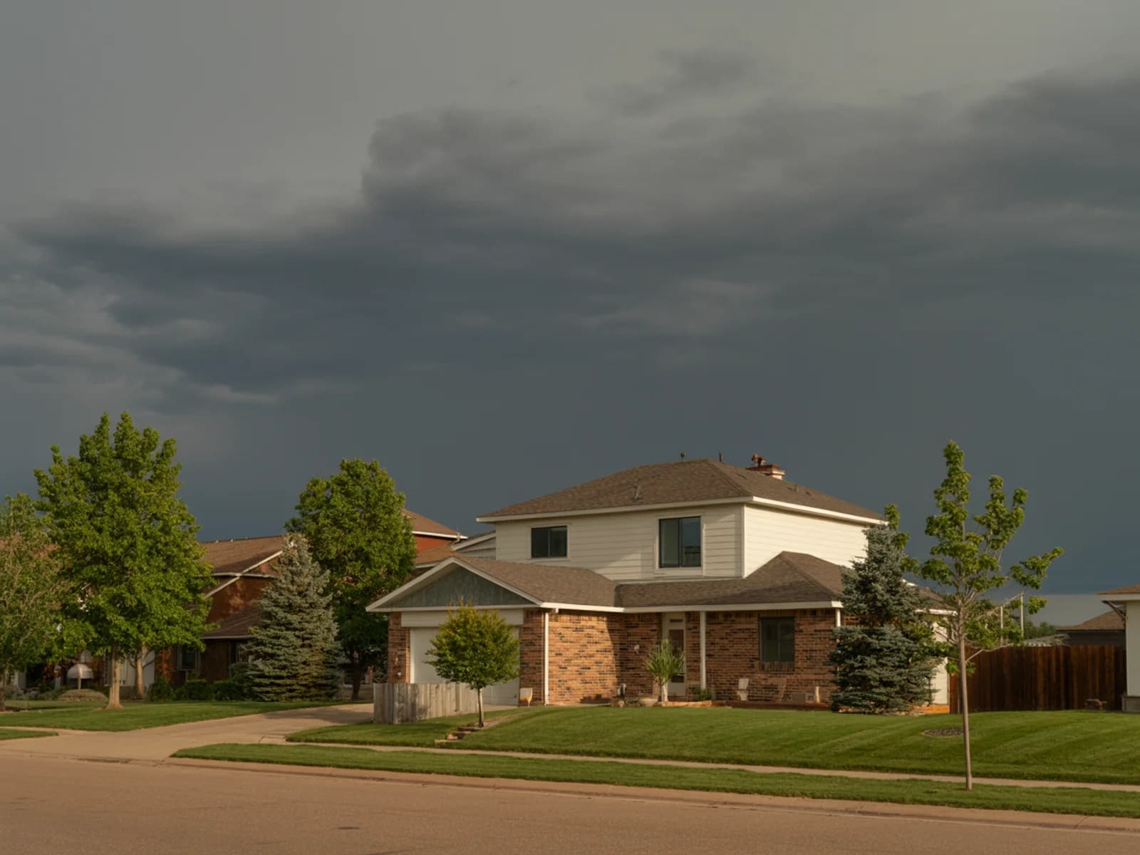 Colorado homes carry Colorado risk A Front Range Colorado home in late afternoon light with storm clouds gathering behind the roofline.